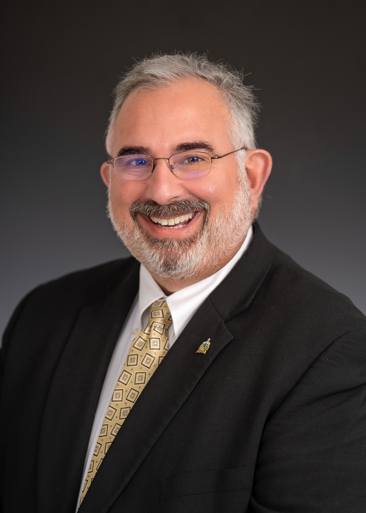 Pepper gray bearded white man in black suit with white shirt and red tie