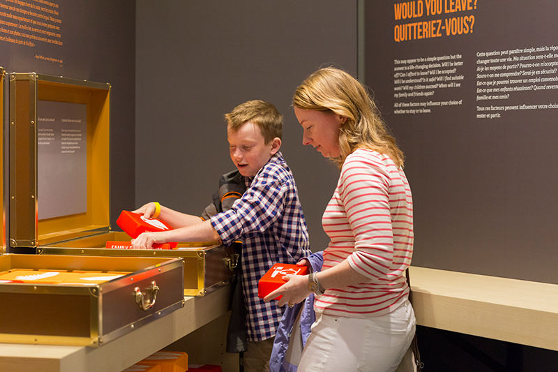 A woman and young boy stand next to an interactive display at the museum.