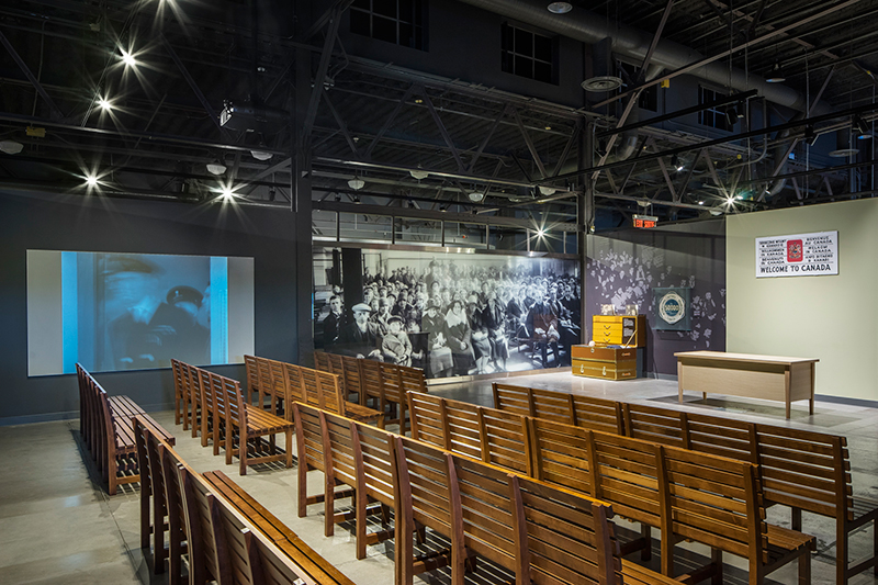 A large room with wooden benches, luggage and tables spread throughout.