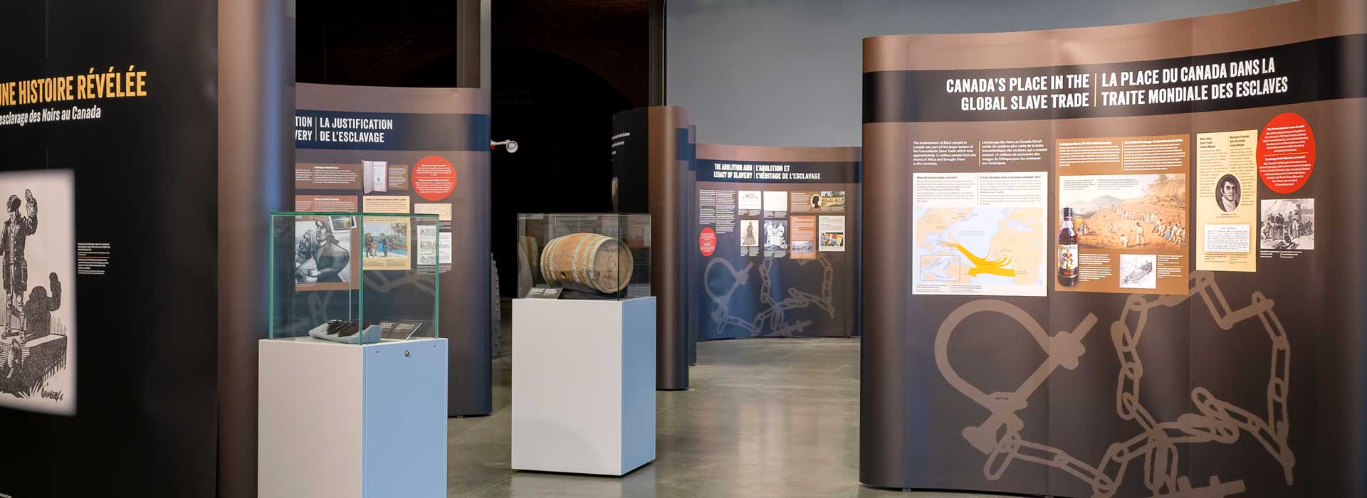 Freestanding, curved exhibition panels, with text and images arranged under the title Canada's Place in the Global Slave Trade.