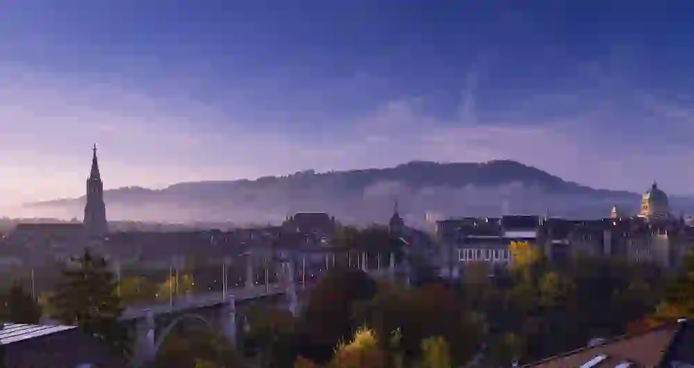 L'aube se pose sur Berne et plonge la ville dans une douce lumière, tandis que des nappes de brouillard enchantent la scène pittoresque autour de la cathédrale et des bâtiments historiques.