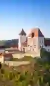 Schloss Burgdorf thront majestätisch auf einem Felsvorsprung, umgeben von sattgrüner Natur und einem klaren Himmel, was eine Atmosphäre von historischer Bedeutung und zeitloser Schönheit vermittelt.