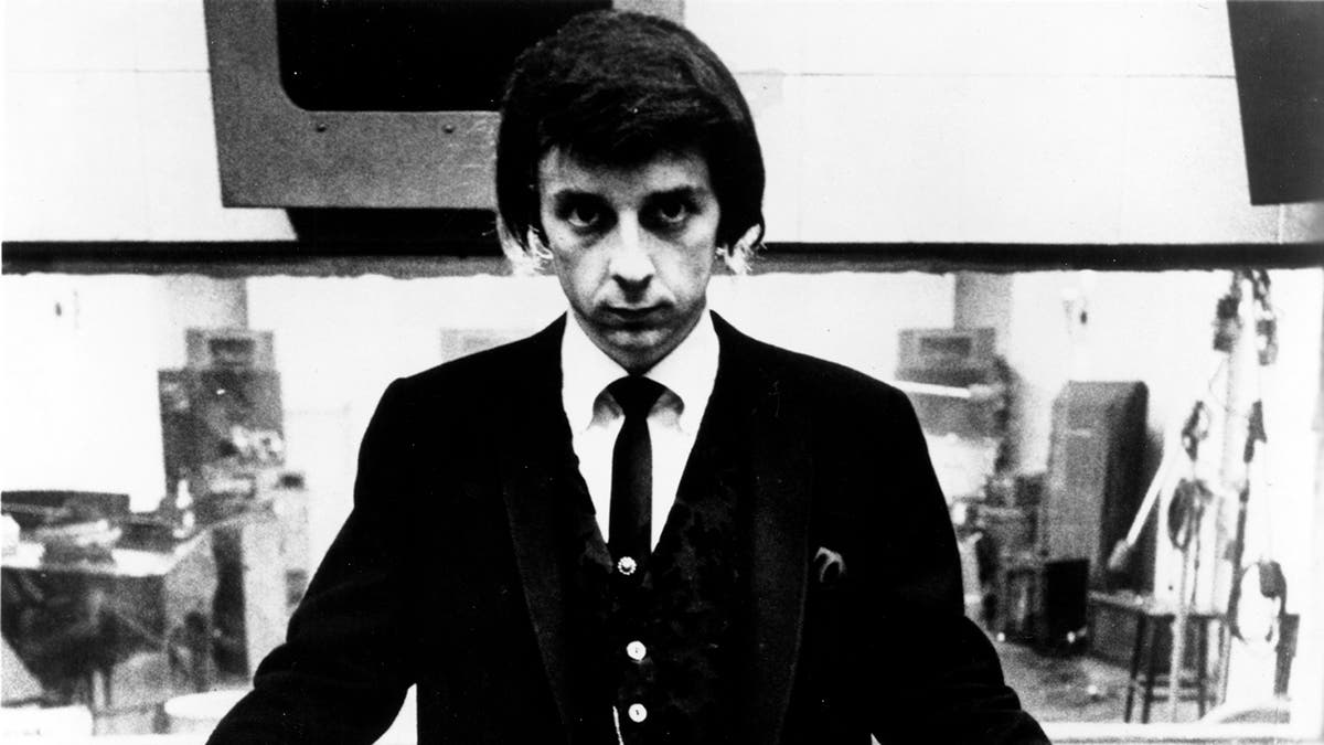 Phil Spector wearing a button down cardigan and a black skinny tie.