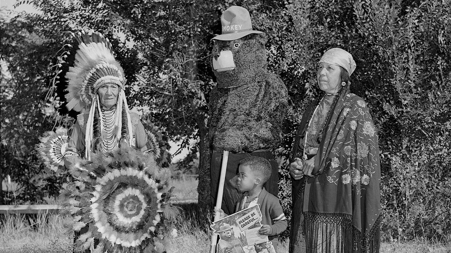 Smokey the Bear, Flathead (Salish) chief Paul Charlo, his wife, and young Allen Thompson pose.