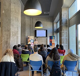 Personnes assises dans une salle, écoutant et regardant une présentation powerpoint