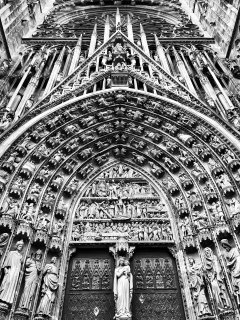 Looking up at the intricately detailed carvings on the main door of a cathedral.