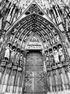 A cathedral door surrounded by intricate carvings of statues.