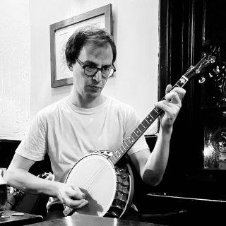 A man playing banjo with a look of concentration on his face.