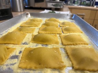 A tray of golden yellow ravioli parcels.