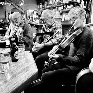 A row of musicians including fiddles and pipes.