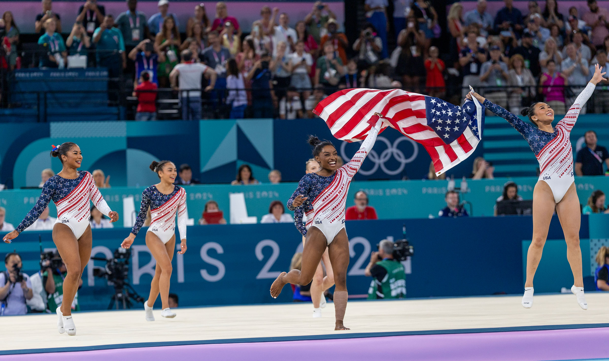 Simone Biles and Sunisa Lee of the United States celebrate with the U.S. flag