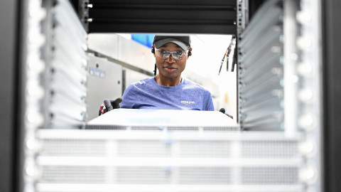 A photo of a data center technician behind a server rack.