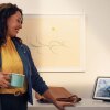 Una mujer tomando un café y disfrutando de un dispositivo Echo. 