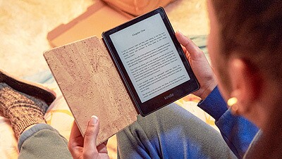 An overhead view of a woman holding an Amazon Kindle. 