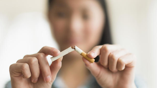 Mixed race teenage girl breaking cigarette in half 