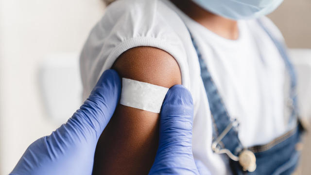 Covid 19 measles, ebola vaccinated. Doctor pediatrician injecting making vaccine to little african girl in medical clinic. Nurse applying medical patch after injection 