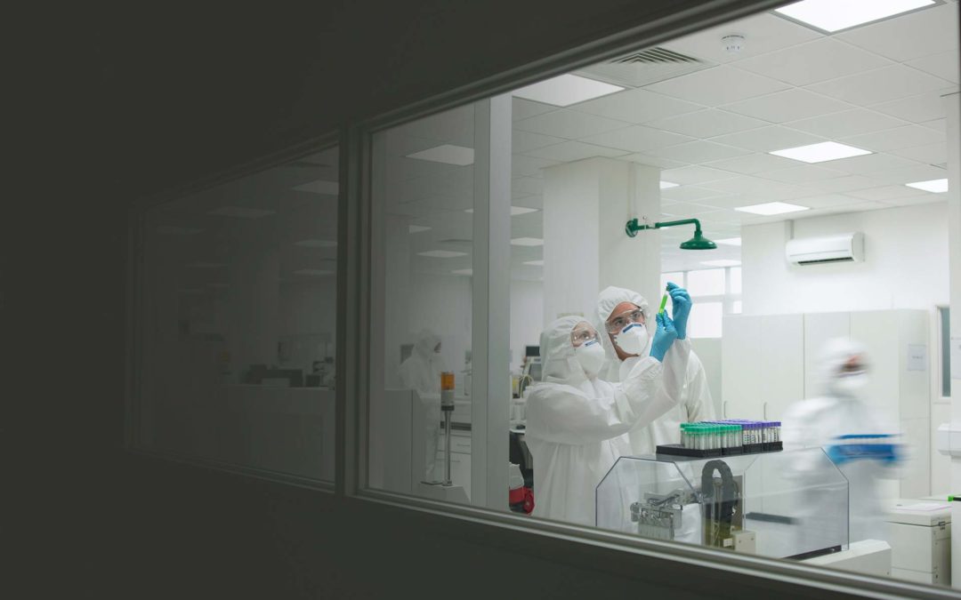 Two scientists wearing protective clothing and masks, evaluating a scientific sample.