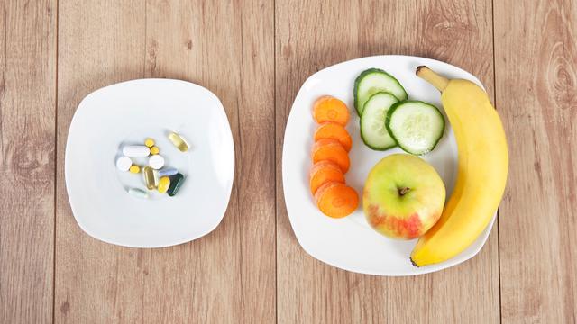 Zwei Teller: auf einem Tabletten, auf dem anderen Obst und Gemüse.