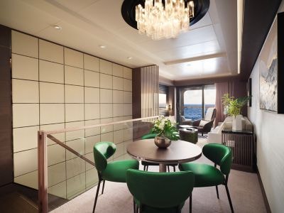 A dining area in a yacht's cabin with green chairs