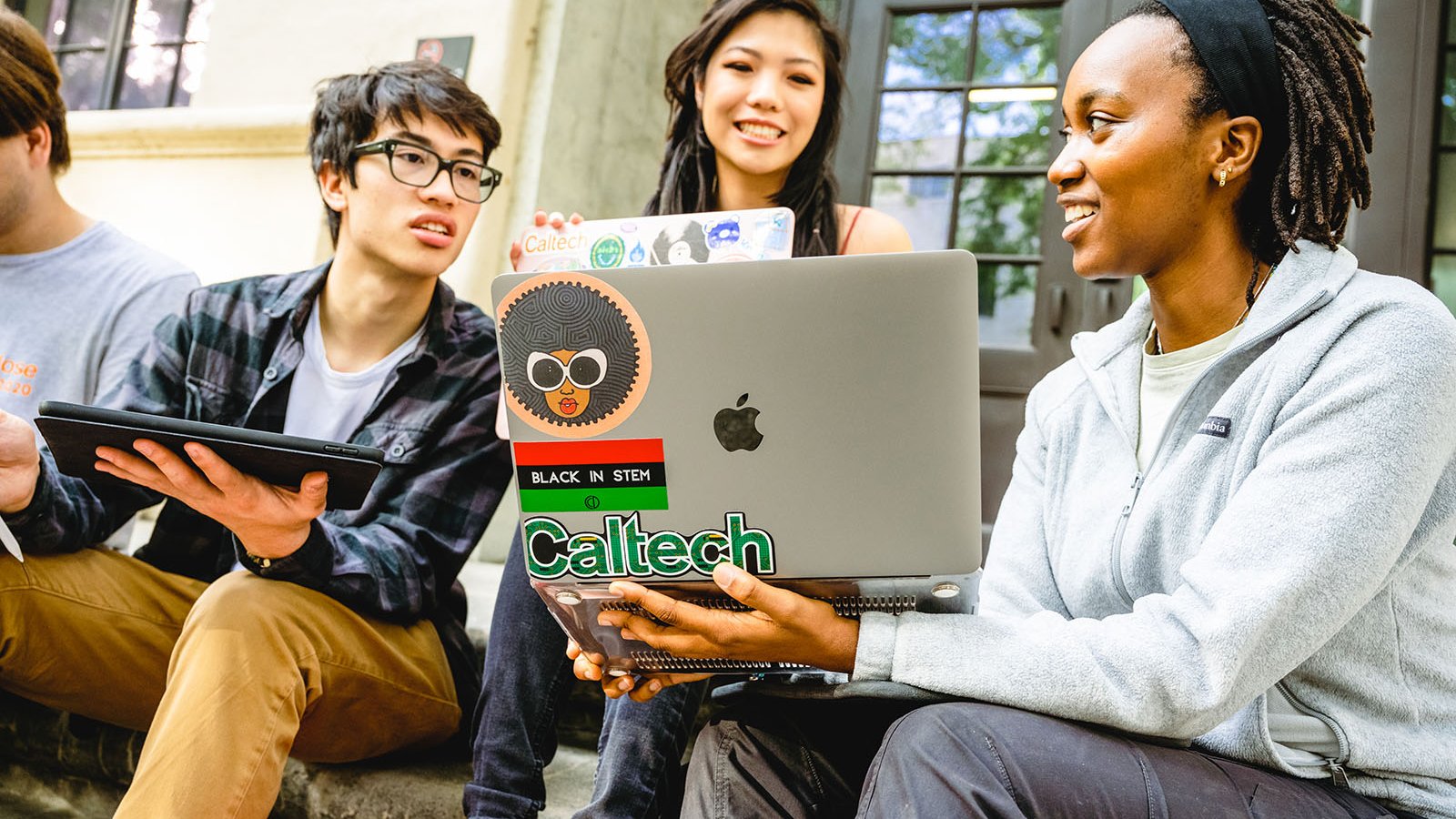 A photo of 3 people looking at a laptop screen