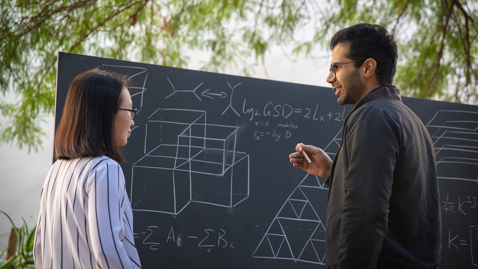 A photo of two people standing next to a blackboard