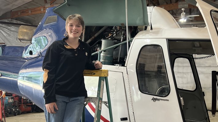 Veronika Voss standing alongside a helicopter in a hangar