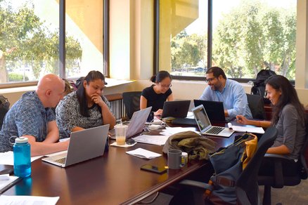 AIM panel members collaborating over laptops at a large table.