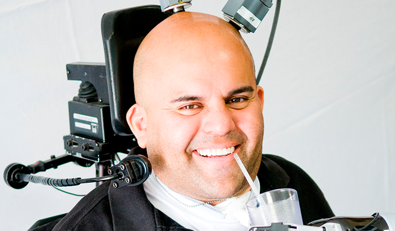 A man uses neuroprosthetics to drink from a glass.