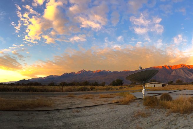 Panoramic view of Owens Valley Radio Observatory with sunrise over mountains in background.