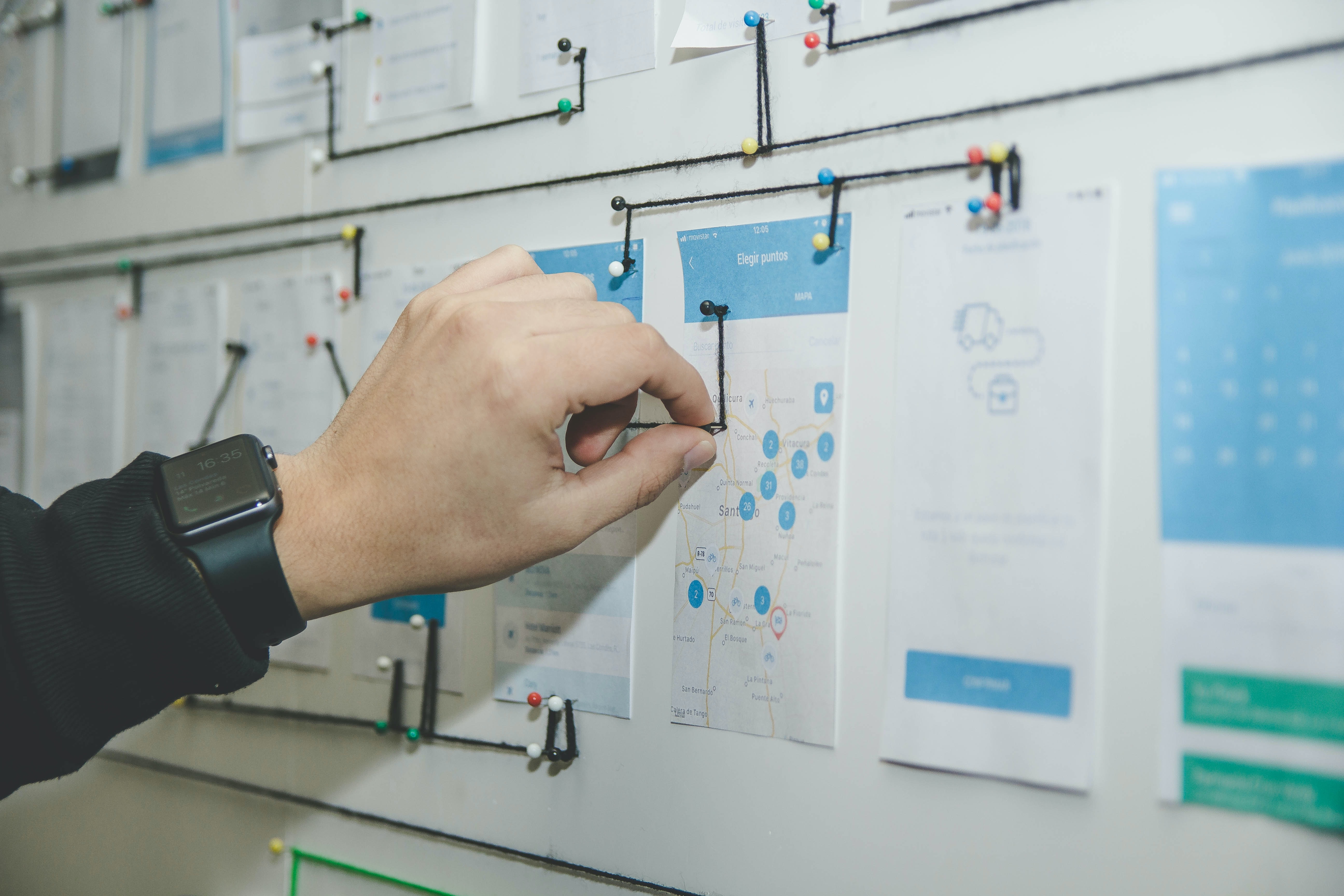 Person attaching string to a mind map on a wall