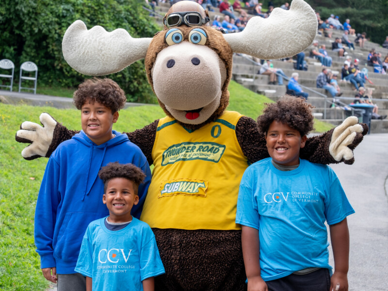 Speedbump the moose posing with three kids in CCV shirts.