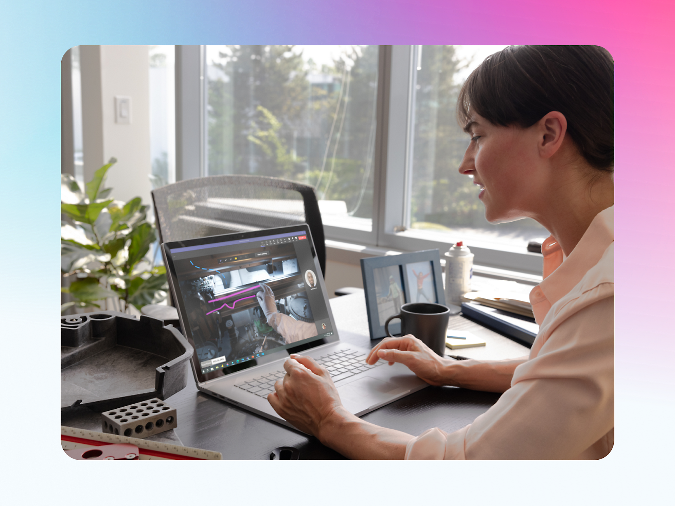 A woman sits at her desk, engaged in a video conference call on her laptop, with a coffee mug