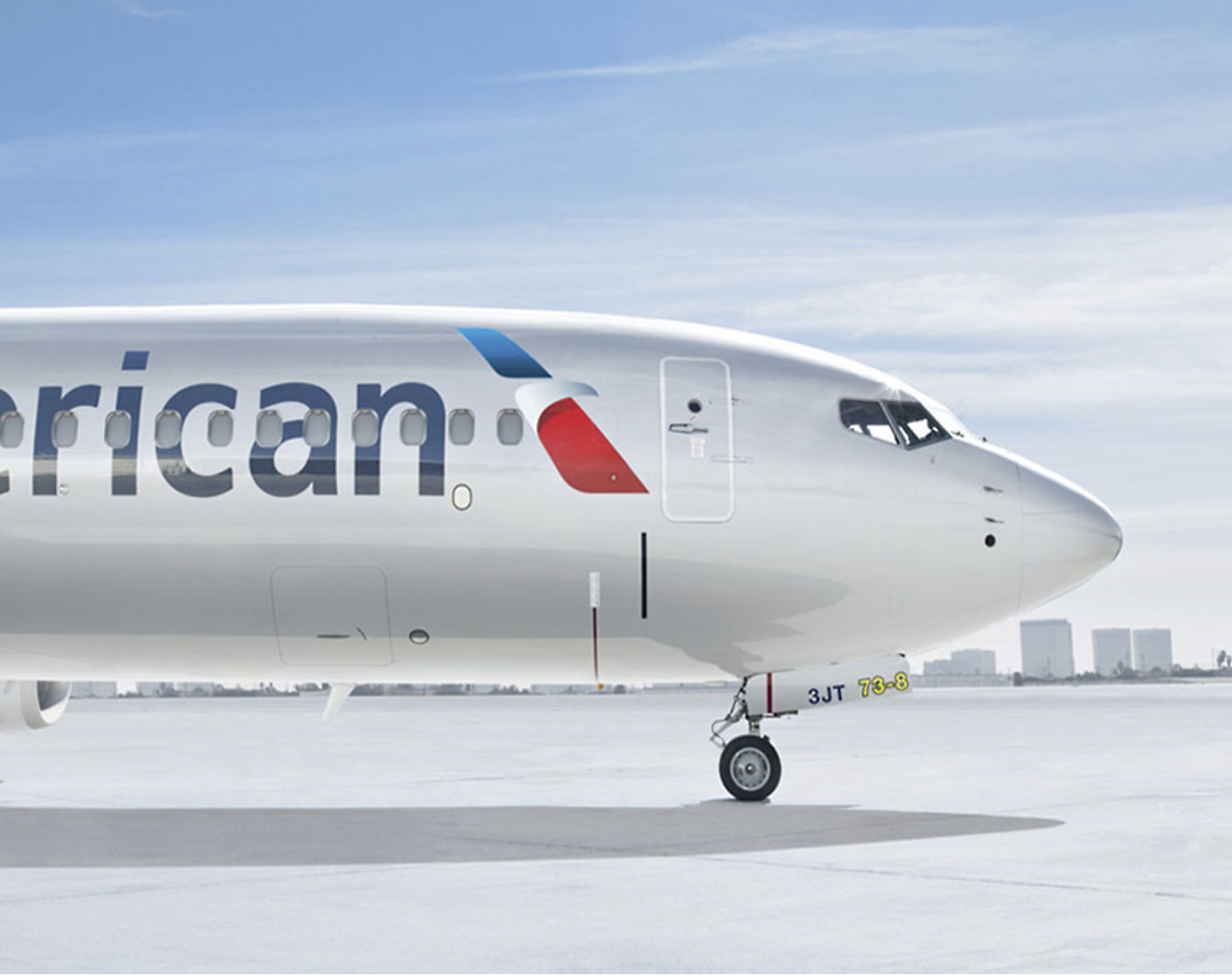 Front view of an American Airlines airplane parked on the tarmac under a clear sky.