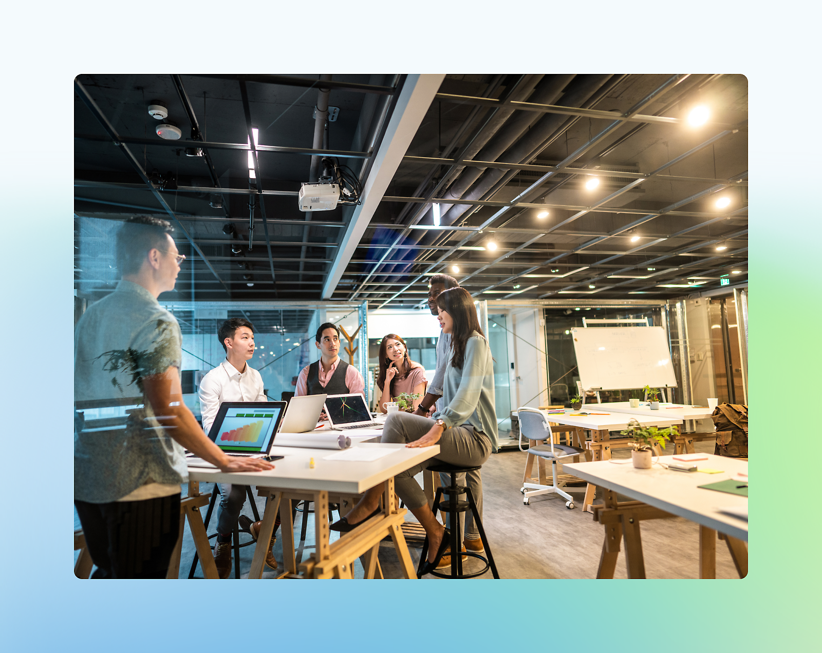 A group of five diverse professionals engaged in a discussion around a high table in a modern office setting