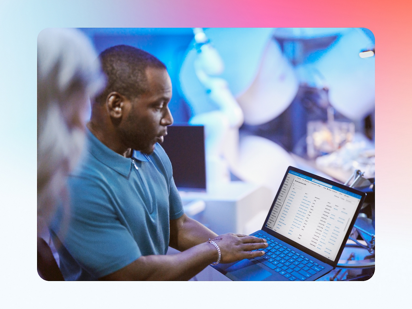 Man reviewing data on a laptop in a busy office setting with colleagues surrounding him.