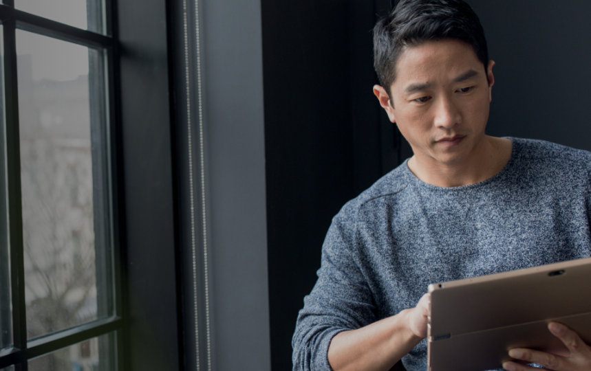 Closeup of a businessperson by window using a tablet.