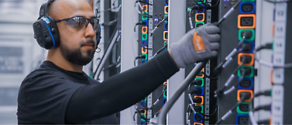 A man in a headset is working on a server rack.