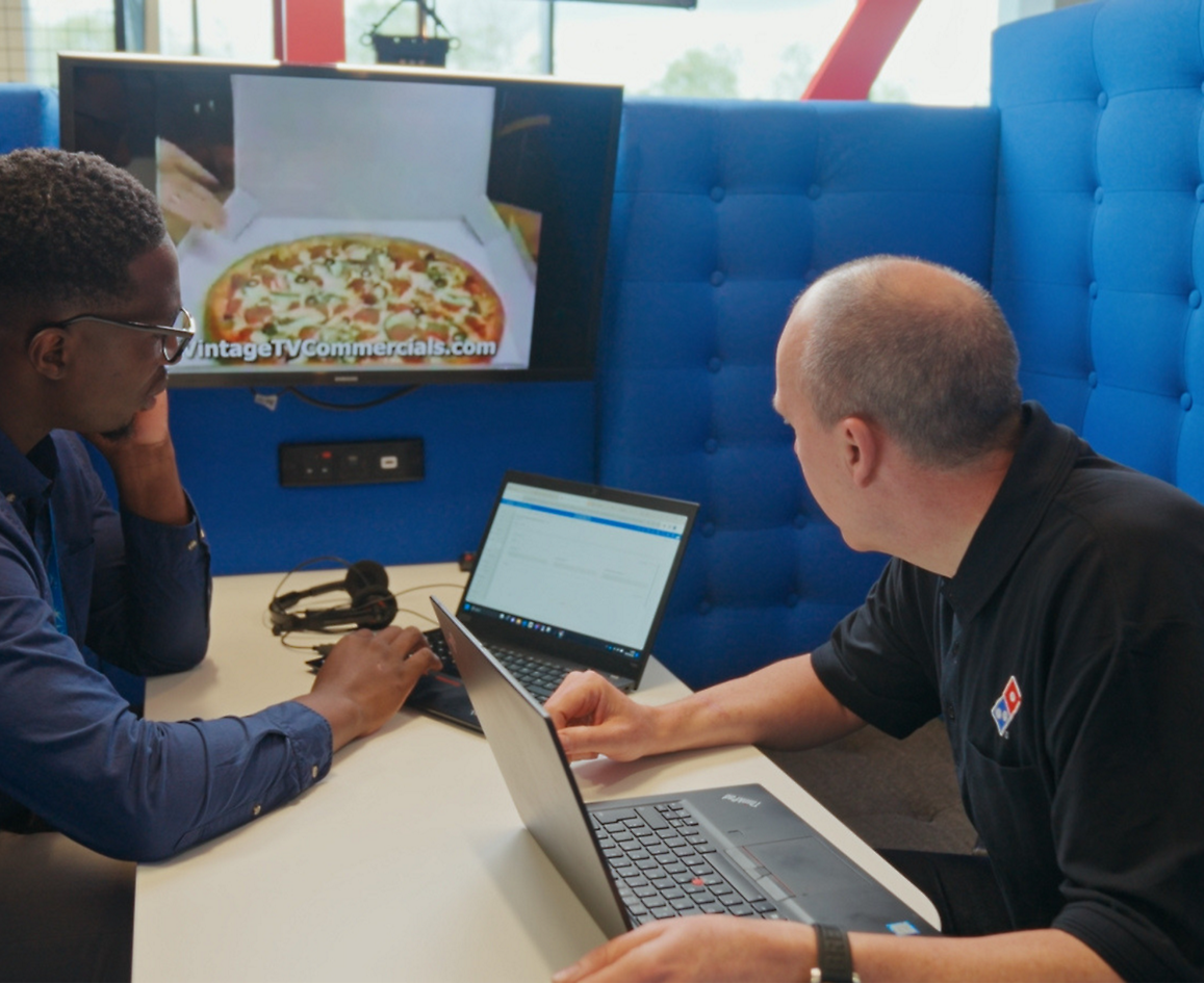 Two persons sitting with laptop and discussing about Dominos pizza