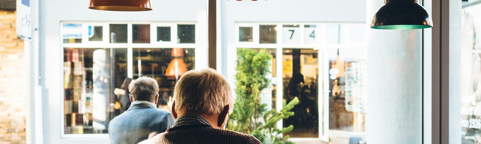 This shows a man sitting at a table at a coffee shop.