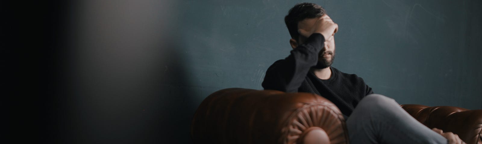 Anxious and depressed man on couch with head in hands