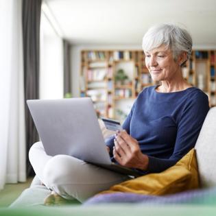 Senior woman using credit card while doing online shopping on laptop at home