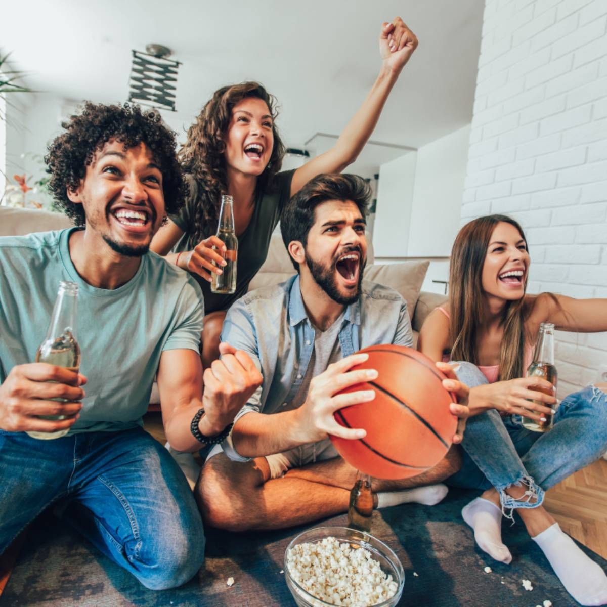 Group of friends with drinks watching a basketball game. 