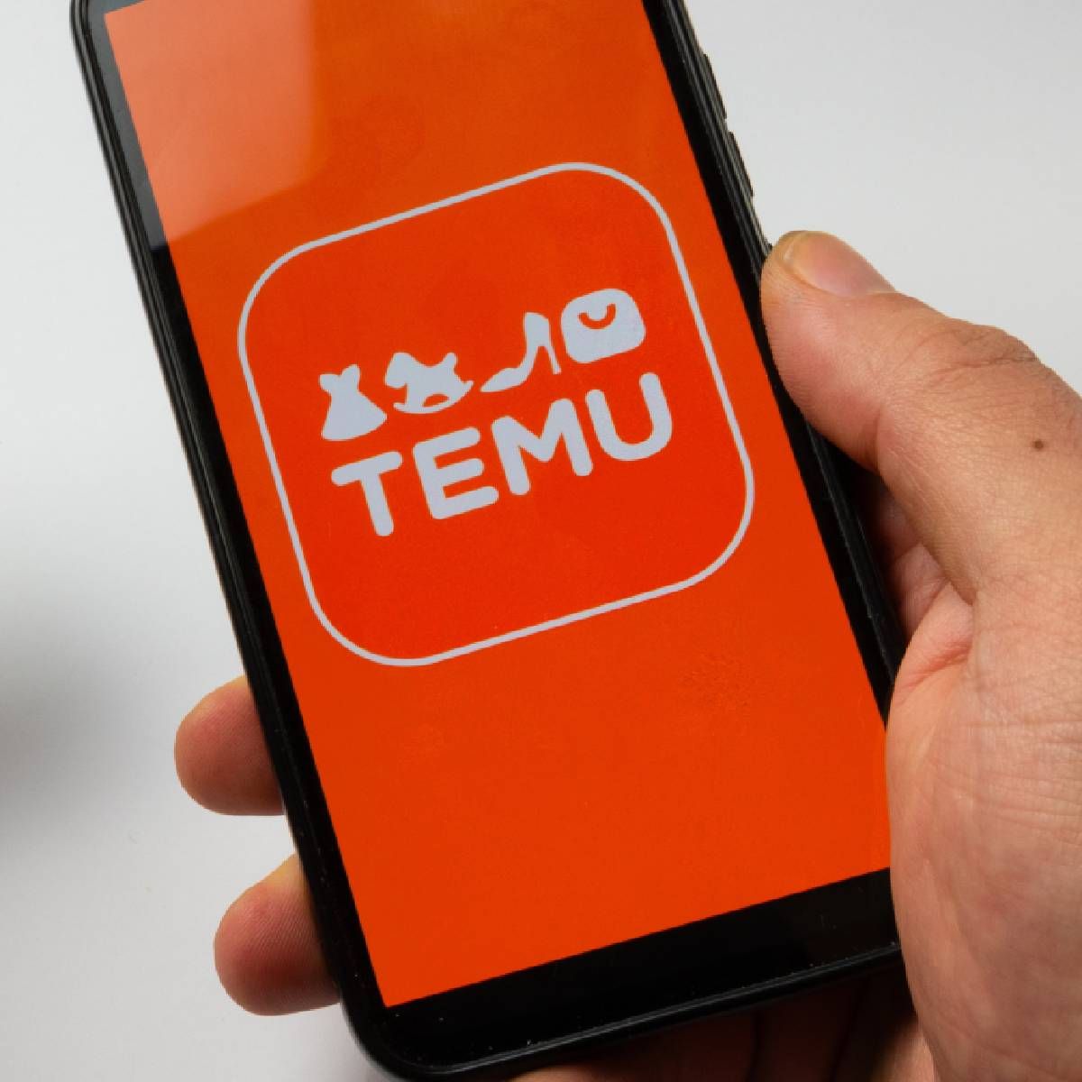 Person holding smartphone with Temu app on screen