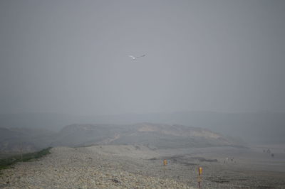 Airplane flying over land against sky