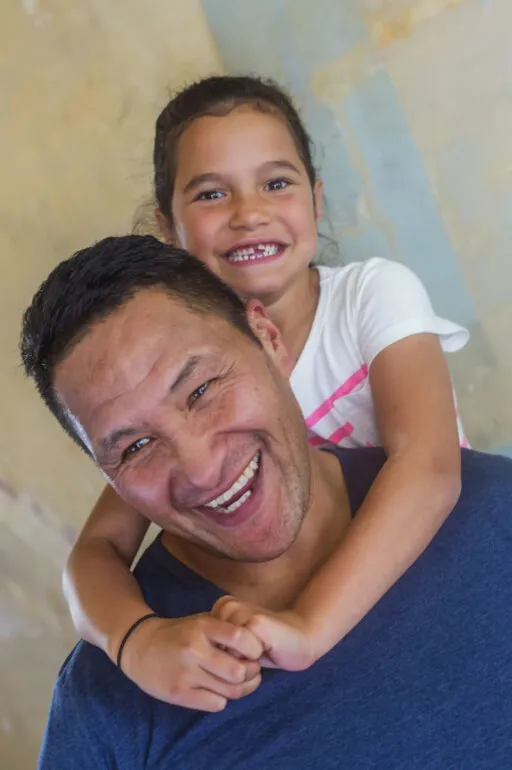 An older man with a little girl on his shoulders smiling.