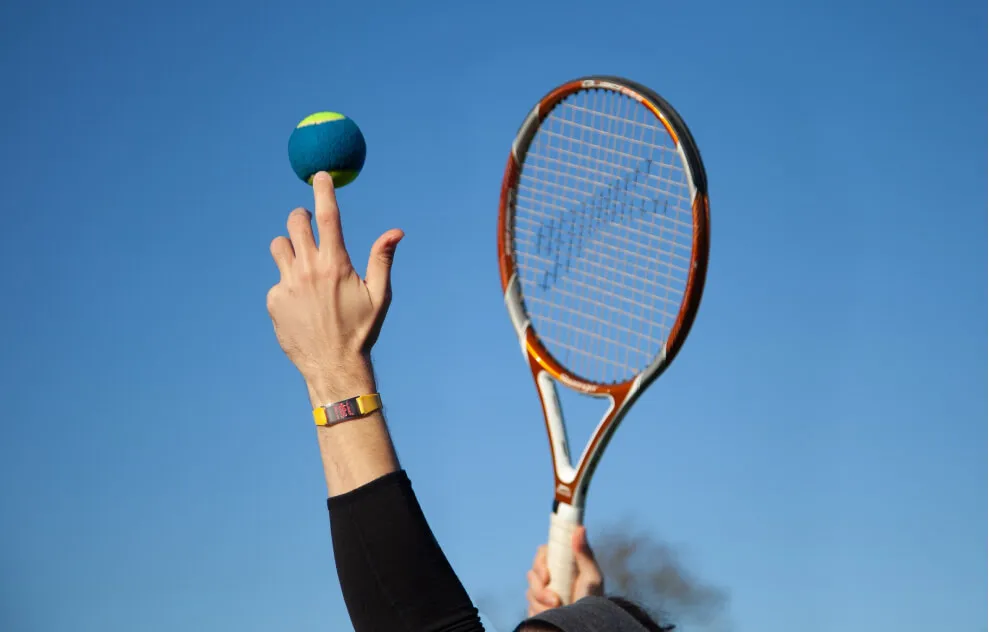 Hands throwing a tennis ball into the air ready to be served