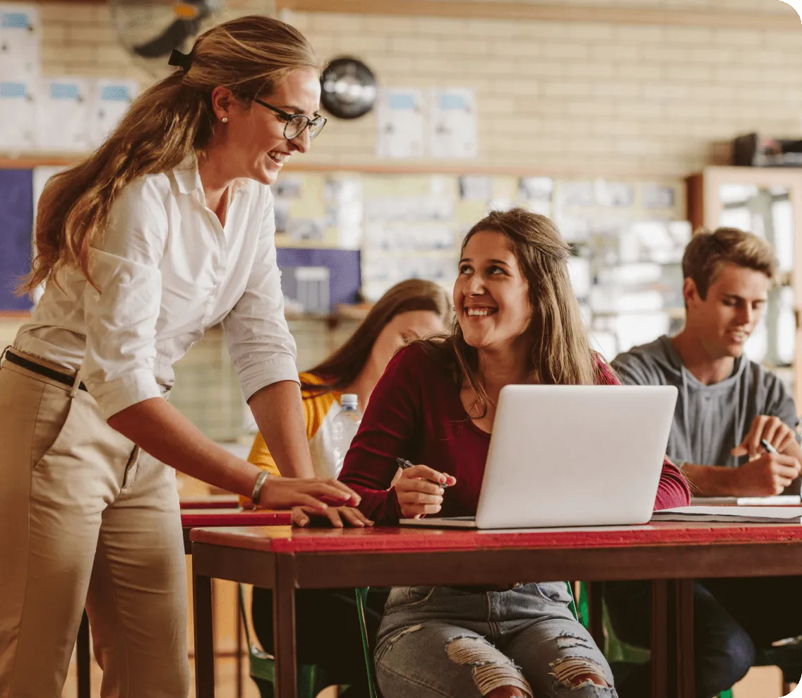 teacher assisting student at their desk.