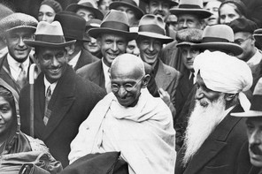 A black and white photograph of Gandhi in a crowd