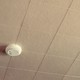 A beige tiled ceiling with a smoke alarm on it