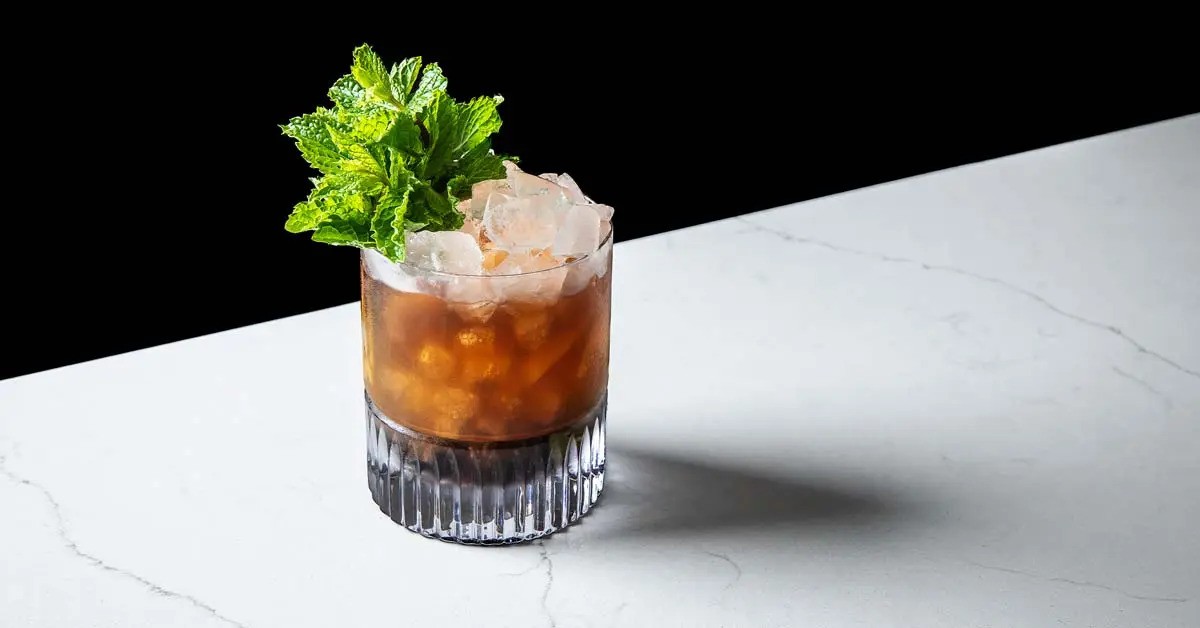 A cocktail garnished with a robust sprig of mint.